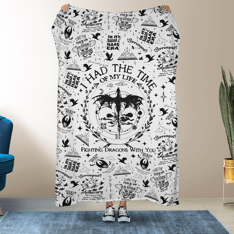 May include: White blanket with a black graphic design. The design includes text that reads "I HAD THE TIME OF MY LIFE FIGHTING DRAGONS WITH YOU" and other text. The blanket has a dragon and floral design.