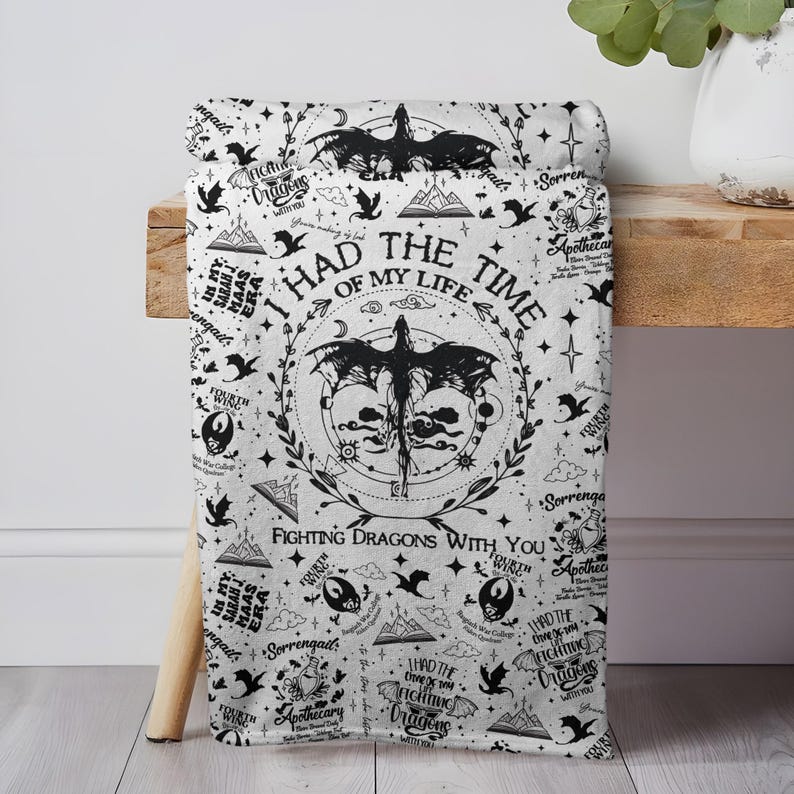 May include: White blanket with a black dragon and text design. The blanket features the phrase "I had the time of my life fighting dragons with you" and other graphics. The blanket is draped over a wooden surface.