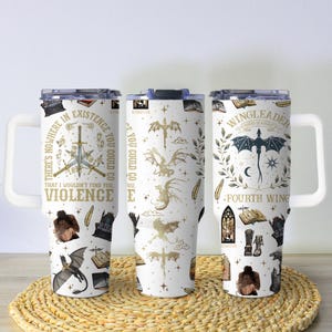May include: Three white travel mugs with fantasy-themed designs. One mug features a sword and text that reads "THERE'S NOWHERE IN EXISTENCE THAT I WOULDN'T FIND YOU, VIOLENCE." Another mug has dragon illustrations. The third mug has a dragon and the text "WINGLEADER, FOURTH WING."