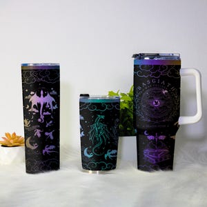 May include: Three black insulated tumblers with dragon designs. One tall tumbler features a purple and pink dragon with the text "Save a Dragon Ride a Dragon". The middle tumbler has a teal dragon. The largest tumbler has the text "Basgiath War College".