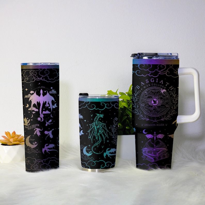 May include: Three black insulated tumblers with dragon designs. One tall tumbler features a purple and pink dragon with the text "Save a Dragon Ride a Dragon". The middle tumbler has a teal dragon. The largest tumbler has the text "Basgiath War College".