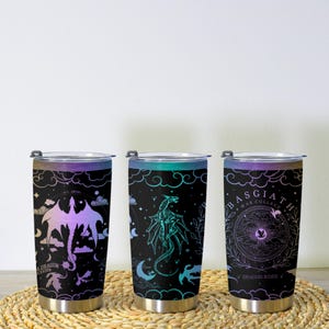 May include: Three stainless steel insulated tumblers with black backgrounds and dragon designs. Each tumbler features a different dragon illustration in shades of purple, teal, and blue, with text that reads "A Dragon's Lair", "Basgiath War College", and "Dragon Rider".