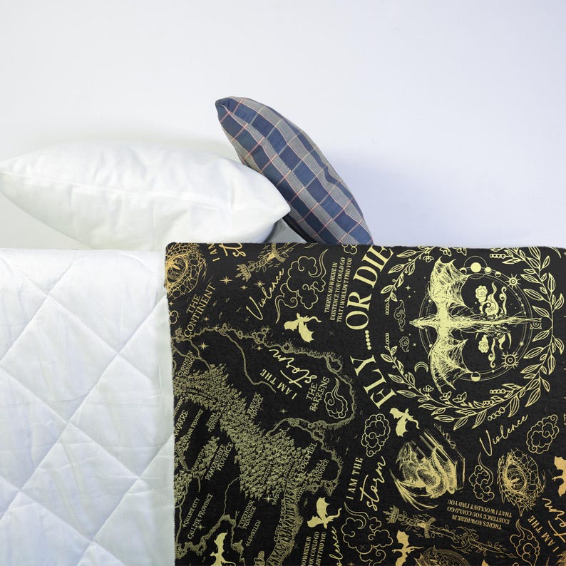 May include: A black and gold patterned blanket with text and illustrations, including a map and the words "Fly or Die". The blanket is paired with white and plaid pillows, creating a cozy bedding set.
