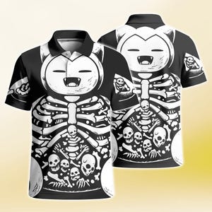 Può includere: Una polo a maniche corte bianca e nera con una stampa grafica di una testa di personaggio dei cartoni animati con un ampio sorriso. L'area del busto mostra una gabbia toracica scheletrica dettagliata e una collezione di teschi e ossa umane.