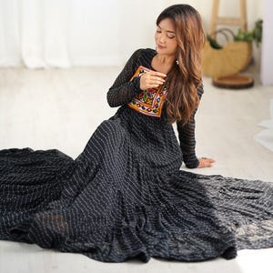 May include: A black maxi dress with white polka dots and colorful embroidery on the bodice. The dress has a flowing silhouette and is perfect for a special occasion.