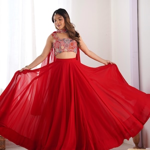May include: A red, flowing skirt with a matching red top featuring a colorful, circular pattern. The top has a halter neckline and a cropped style.