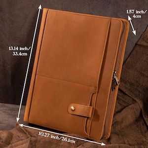 Może przedstawiać: Brązowe skórzane portfolio z zapięciem na zamek błyskawiczny i zatrzask. Portfolio ma wymiary 33,4 cm na 26,1 cm i grubość 4 cm. Skóra ma teksturowany wygląd.