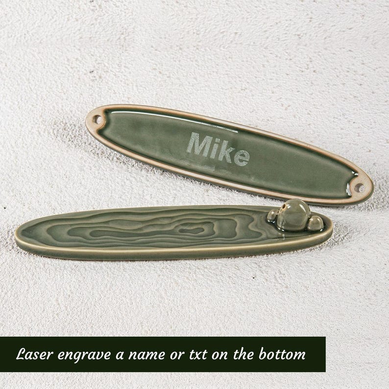 May include: Two green ceramic incense holders. One is engraved with the name "Mike". The other has a textured design and a small decorative element. The text "Laser engrave a name or txt on the bottom" is at the bottom.