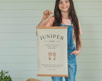 May include: A personalized Juniper Rose birth announcement on a canvas banner. The banner includes the baby's name, birth date, time, weight, and length (21 inches). The banner is held by a person.