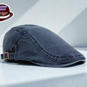 May include: A denim-style, dark blue flat cap with a curved brim. The cap features a stitched design and a small, adjustable buckle on the side. The image also includes a logo with the text "RUTASHIRI DRINSON UNIQUE DESIGNS HAT / CAPS".