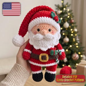 Op de afbeelding: Een gehaakte kerstmanpop gemaakt van rood, wit en zwart garen. De figuur heeft een rode muts met een witte pompon, een witte baard, een bruine riem met een gele gesp en zwarte laarzen. In één hand houdt de pop een klein groen cadeautje en een zuurstok.