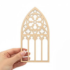 May include: A laser-cut wooden gothic window design. The window features an arched top with intricate floral and geometric cutouts. The natural wood color provides a neutral base for crafting or decoration.