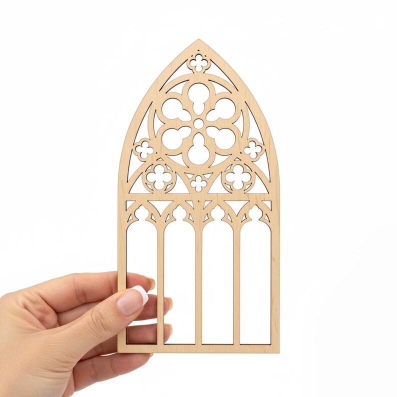 May include: A laser-cut wooden gothic window design. The window features an arched top with intricate floral and geometric cutouts. The natural wood color provides a neutral base for crafting or decoration.