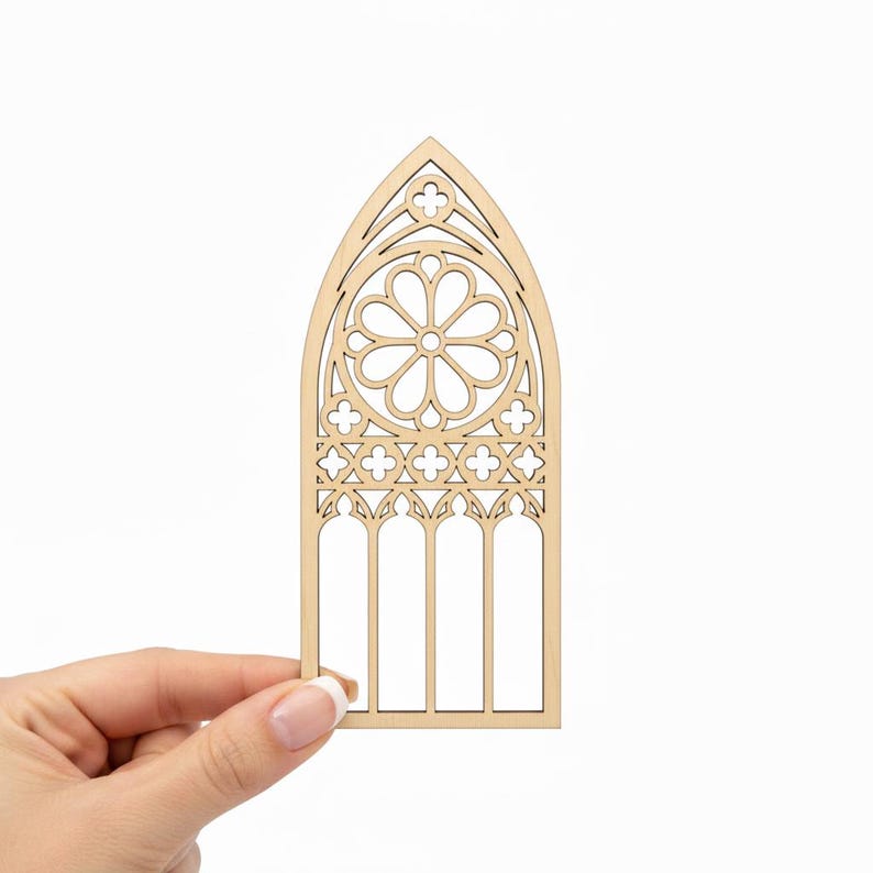 May include: A laser-cut wooden gothic window design. The window features a central floral pattern, intricate tracery, and arched top. The natural wood color provides a neutral base for crafting or decoration.