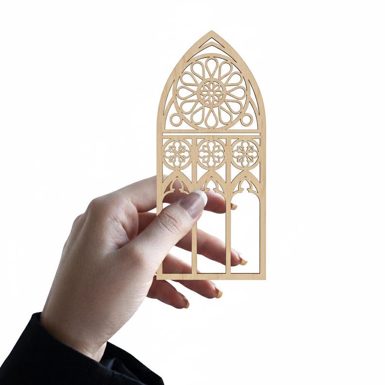 May include: A laser-cut wooden decorative window panel with an arched top. The panel features a detailed design of a rose window and gothic-style tracery. The natural wood color provides a neutral tone, suitable for various decor styles.