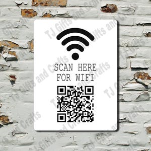 May include: A white rectangular sign with black text and graphics. The sign displays a WiFi symbol above the words "SCAN HERE FOR WIFI" and a QR code. The sign is mounted on a weathered, white brick wall.