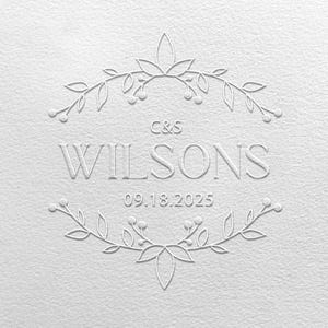 Op de afbeelding: Wit reliëfontwerp met de naam "WILSONS", initialen "C&S" en de datum "09.18.2025". Het ontwerp is omgeven door een bloemenrand met bladeren en bessen.