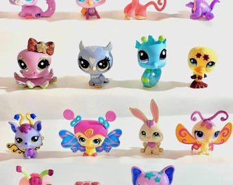 May include: A collection of sixteen small, stylized animal figurines with large eyes, featuring various creatures including a purple cat, pink monkey, dragon, octopus, owl, seahorse, duck, butterfly-winged insects, rabbit, turtle, and bat.