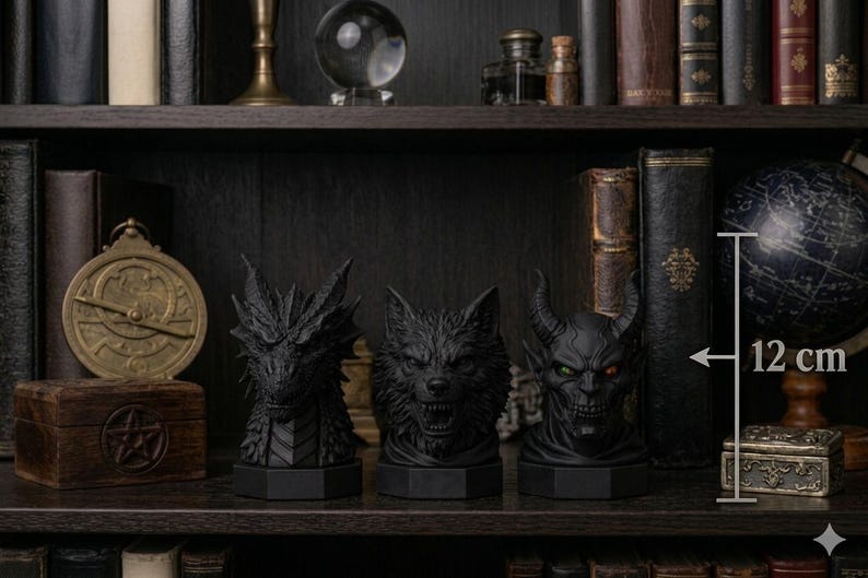 Pode incluir: Tr&ecirc;s bustos negros de fantasia, um drag&atilde;o, um lobo e um dem&oacute;nio, cada um com cerca de 12 cm de altura, s&atilde;o exibidos numa prateleira. O drag&atilde;o tem escamas detalhadas, o lobo mostra os dentes e o dem&oacute;nio tem chifres e olhos brilhantes. A prateleira &eacute; rodeada por livros e objetos decorativos.