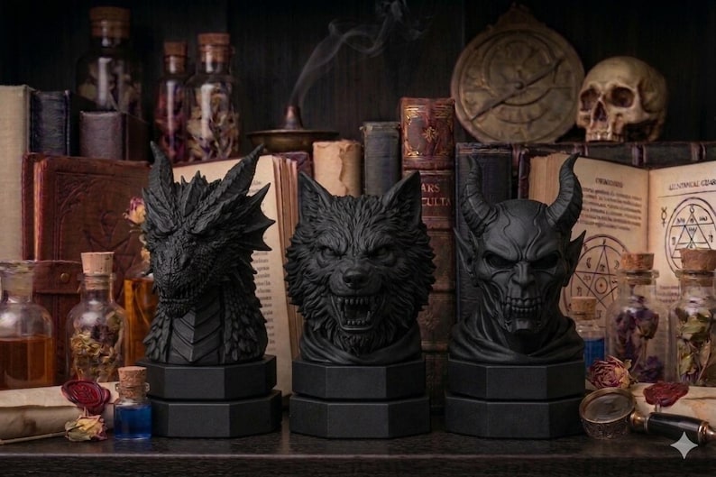Pode incluir: Tr&ecirc;s bustos negros de fantasia: um drag&atilde;o, um lobo e um dem&ocirc;nio. Cada busto est&aacute; sobre uma base hexagonal. O fundo inclui livros, frascos de po&ccedil;&otilde;es e uma caveira, criando um tema g&oacute;tico ou de fantasia.
