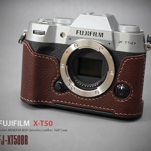 Könnte beinhalten: Eine Fujifilm X-T50 Kamera mit einer braunen Leder-Halbhülle. Die Kamera ist silber und schwarz mit dem Fujifilm-Logo. Die Lederhülle ist genäht und umschließt das Kameragehäuse. Der Text "FUJIFILM X-T50" und "FJ-XT50BR" sind sichtbar.