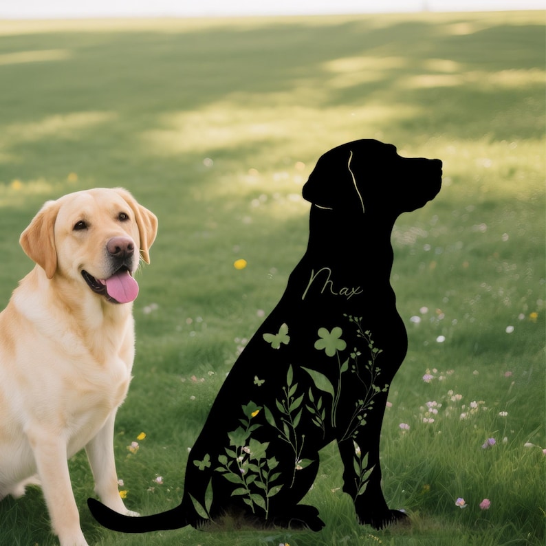 May include: A yellow Labrador Retriever sits next to a black silhouette of a dog with floral and butterfly accents. The silhouette has the name "Max" in cursive. The dogs are on a grassy field.