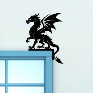May include: A black dragon silhouette, perched on a blue window frame. The dragon has detailed wings, a spiky tail, and a fierce expression. This decorative piece adds a touch of fantasy to any space. The dragon is a symbol of power and protection.