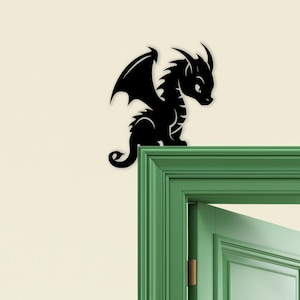 May include: A black dragon silhouette with detailed wings, horns, and a curled tail. The dragon is perched on a green door frame against a cream-colored wall. The dragon is a decorative element.