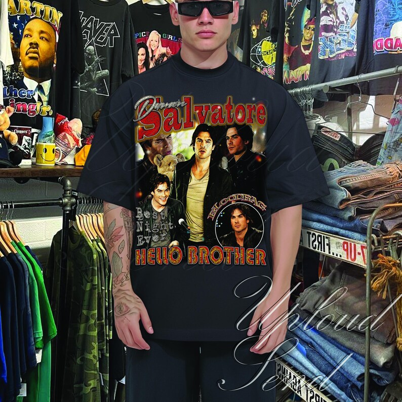 Pu&ograve; includere: T-shirt nera con una grafica che presenta la parola "Salvatore" in rosso e bianco, con immagini di attori. La maglietta ha anche il testo "Best Night Ever" e "Hello Brother".