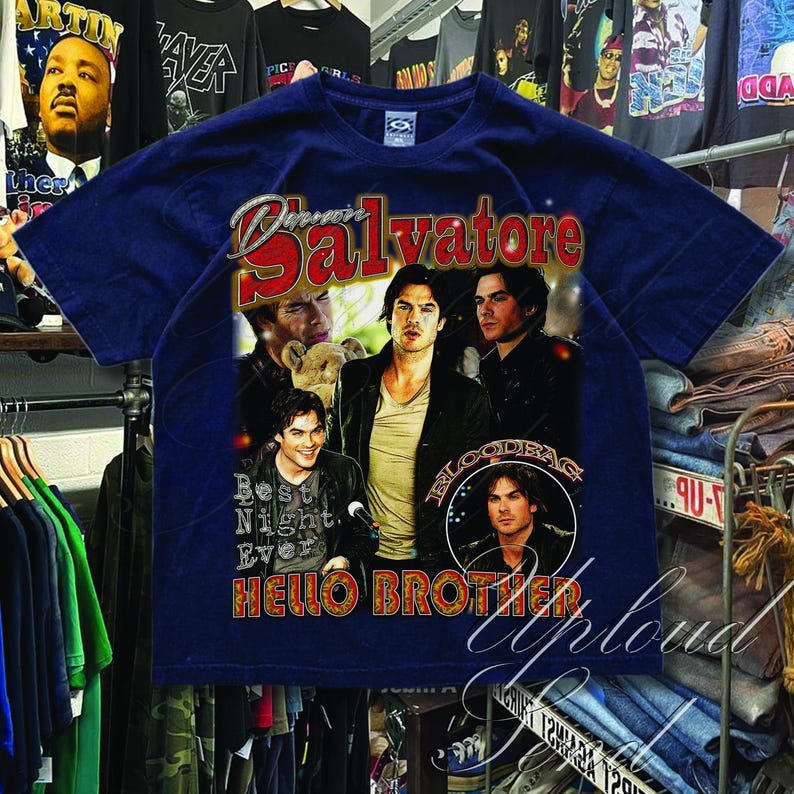 Pu&ograve; includere: T-shirt blu navy con una grafica di diversi uomini e la scritta "Damon Salvatore" in rosso e oro. La maglietta include anche le frasi "Best Night Ever" e "Hello Brother" in stile vintage.