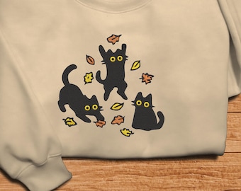 Sudadera bordada con un lindo gato negro saltando sobre las hojas, regalo acogedor para amantes de los gatos, camiseta con ambiente otoñal, camisa bordada acogedora para Halloween otoñal.