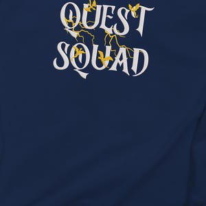 May include: Navy blue sweatshirt with white embroidered text that reads "QUEST SQUAD" with yellow embroidered birds and lightning bolts.