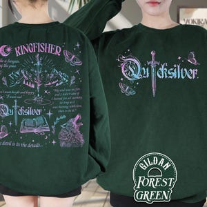 Pu&ograve; includere: Felpa verde foresta con la scritta "Quicksilver" in gradiente, una spada e grafiche di farfalle. Il retro presenta la scritta "Kingfisher", un lupo, montagne e testo. La felpa &egrave; Gildan Forest Green.