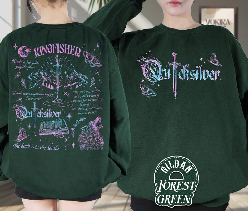 Pu&ograve; includere: Felpa verde foresta con la scritta "Quicksilver" in gradiente, una spada e grafiche di farfalle. Il retro presenta la scritta "Kingfisher", un lupo, montagne e testo. La felpa &egrave; Gildan Forest Green.