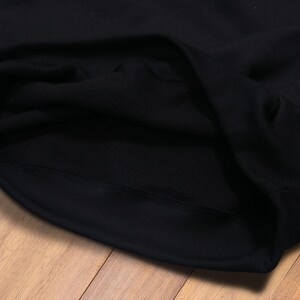 May include: Close-up of the inside of a black hooded sweatshirt. The fabric is soft and the stitching is neat.