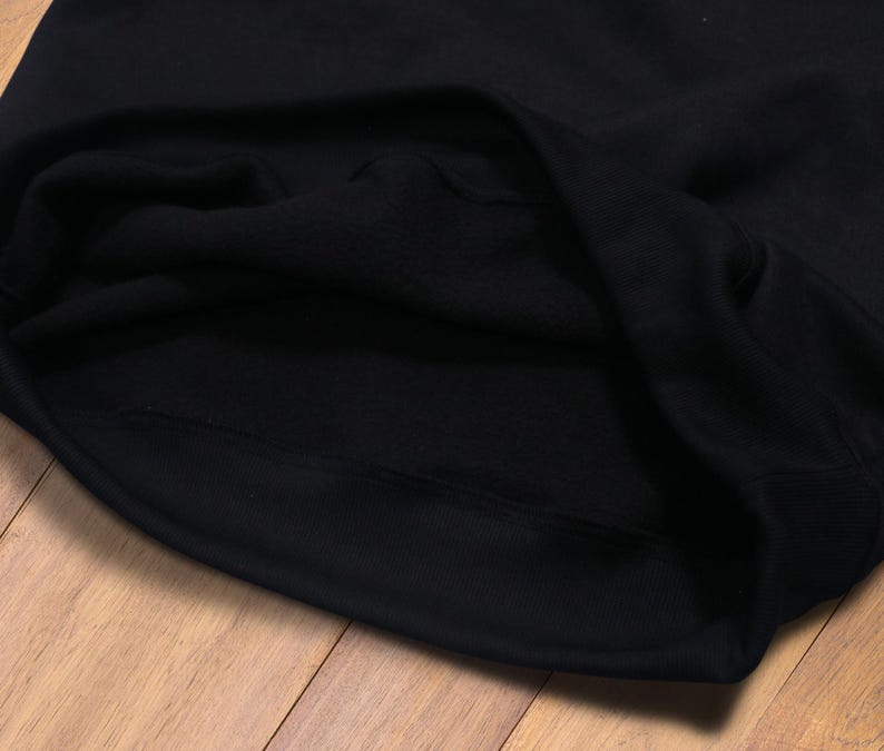 May include: Close-up of the inside of a black hooded sweatshirt. The fabric is soft and the stitching is neat.