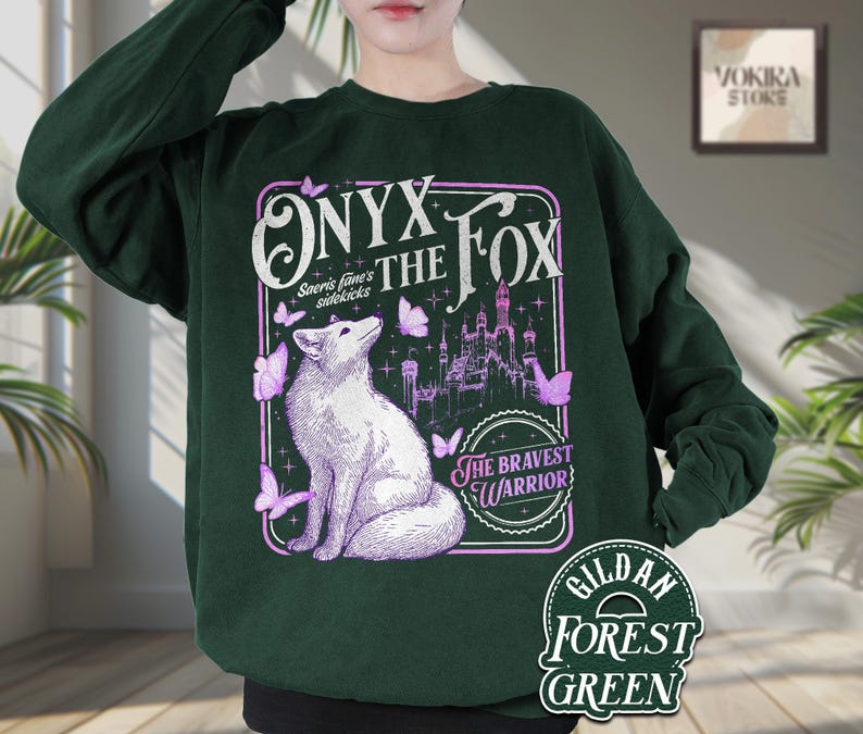 Może przedstawiać: Leśnozielona bluza z nadrukiem białego lisa, motyli i zamku, z napisem "ONYX THE FOX" i "THE BRAVEST WARRIOR". Bluza wykonana jest z materiału Gildan Forest Green.