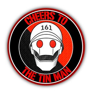 May include: A round sticker featuring a stylized robot head with red eyes and a white helmet. The text "CHEERS TO THE TIN MAN" and the number "161" are in red, set against a black and red background.