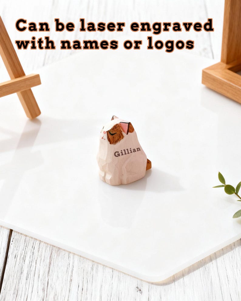 May include: A wooden cat figurine with brown and white markings, engraved with the name "Gillian." The figurine is on a white surface. Text above reads "Can be laser engraved with names or logos."