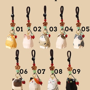 May include: Nine cat-shaped lanyards with varying colors and patterns. Each cat charm is wooden and attached to a brown cord with decorative beads. The text "Cat & Lanyard" is at the top.