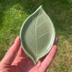 Plato decorativo de cerámica hecho a mano con forma de hoja de color verde tierra.