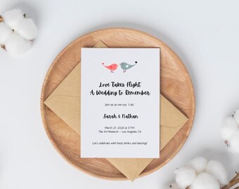 Pode incluir: Um convite de casamento com fundo branco e um envelope castanho. O convite apresenta um par de pássaros, um vermelho e outro azul, com o texto "Love Takes Flight A Wedding to Remember" e os nomes "Sarah & Nathan".