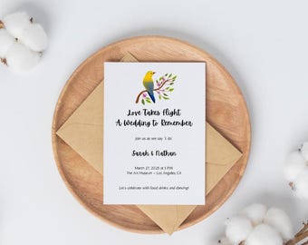 Pode incluir: Um convite de casamento com um pássaro azul e amarelo em um galho com flores rosa. O texto diz "Love Takes Flight A Wedding to Remember" e inclui os nomes "Sarah & Nathan" e a data "March 27, 2025 at 5 PM".
