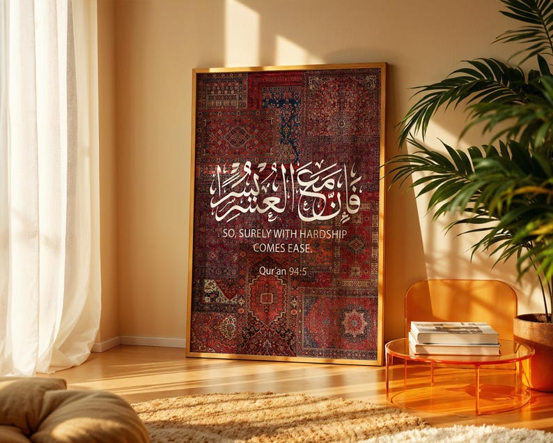 Pu&ograve; includere: Un'opera d'arte incorniciata con un patchwork di motivi di tappeti rossi e bordeaux. Calligrafia araba bianca e testo inglese: "SO, SURELY WITH HARDSHIP COMES EASE. Quran 94:5". L'opera d'arte si trova in una stanza con un'estetica moderna.