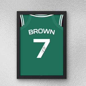 Puede incluir: Impresión enmarcada de una camiseta de baloncesto verde con el nombre "BROWN" y el número "7" en blanco. La camiseta tiene una firma en el número. El marco es negro.