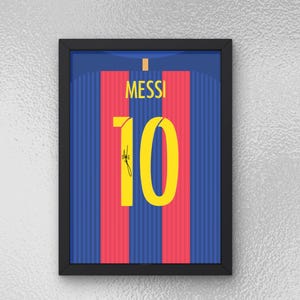 Peut inclure: Impression encadrée d'un maillot de football. Le maillot est à rayures bleues et rouges avec le nom "MESSI" et le numéro "10" en jaune. Le maillot porte une signature sur le numéro 10. Le cadre est noir.