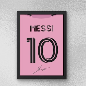 May include: A framed print of a pink football shirt with the name "MESSI" and the number "10" in black. The shirt has a signature at the bottom.