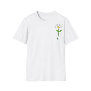 Peut inclure: Un t-shirt blanc à manches courtes avec un petit motif de fleur sur la poitrine supérieure gauche. La fleur possède des pétales blancs, un cœur jaune et une tige verte avec deux petites feuilles vertes s'étendant sur les côtés de la tige.