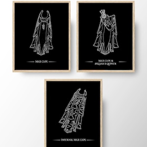 May include: Three framed art prints featuring white line drawings of capes and a quiver on a black background. The text on the prints reads "MAX CAPE", "MAX CAPE & DIZANA'S QUIVER", and "INFERNAL MAX CAPE".