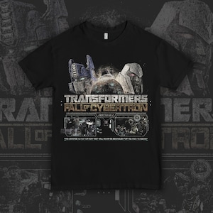 Peut inclure: Un t-shirt noir à manches courtes avec un graphisme représentant Optimus Prime et Megatron au-dessus du texte Transformers Fall of Cybertron. Sous le titre se trouvent deux panneaux rectangulaires montrant des scènes de bataille et le texte This universe no matter how vast will never be big enough for you and I to coexist.